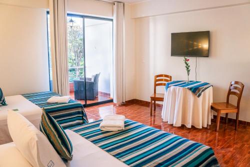 een kamer met drie bedden en een tafel met stoelen bij Casablanca Hotel in San Ramón