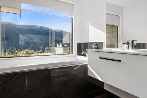 uma casa de banho com uma janela, uma banheira e um lavatório. em Lakehouse Retreat - Whakamaru Holiday Home em Mangakino
