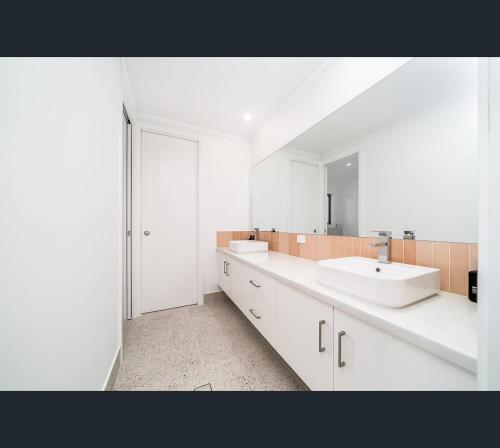 Baño blanco con 2 lavabos y espejo en Brand New Luxury Abode on Shaw, en Wagga Wagga