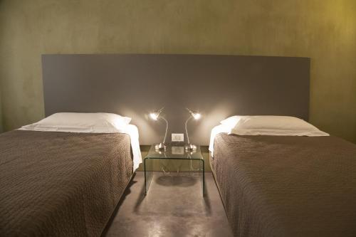 two beds in a room with a table between them at Rosalmar B&B in Palermo
