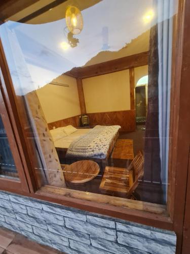 a view through a window of a room with a bed at anavrin in Jibhi