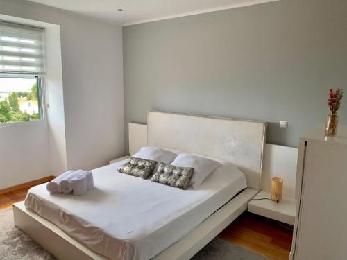 a bedroom with a white bed with two pillows at Retiro das Bananeiras in Horta
