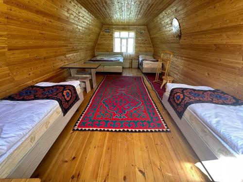a room with two beds and a rug in a log cabin at Bosogo Resort in Pervomayskoye
