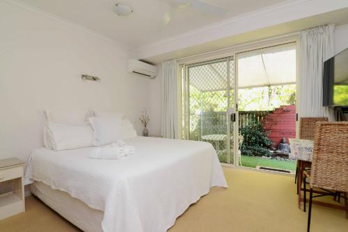 a white bedroom with a bed and a large window at Howie's Place Noosa in Noosaville