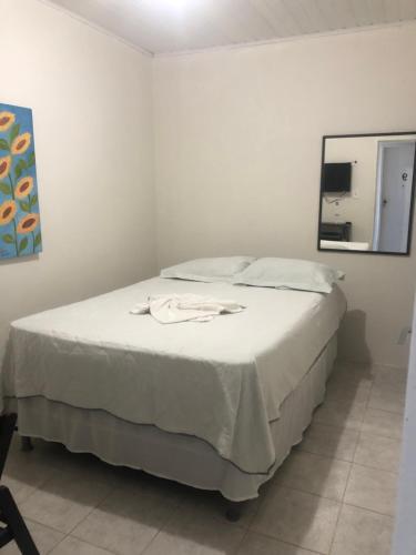 Cama blanca en habitación con espejo en Pousada Aconchego en Aracaju