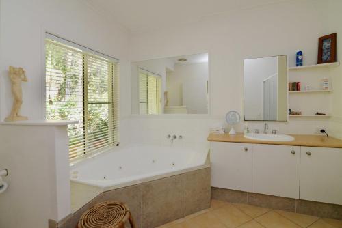 ein Badezimmer mit einer Badewanne, einem Waschbecken und einer Badewanne in der Unterkunft Howie's Place Noosa in Noosaville