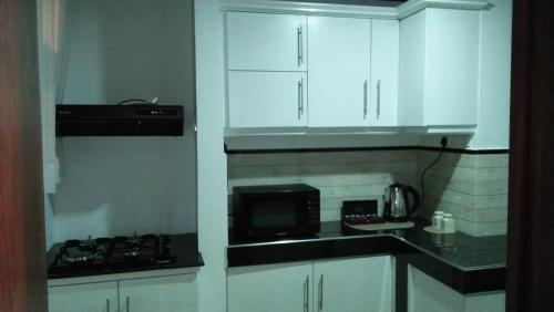 eine Küche mit weißen Schränken und einer Mikrowelle in der Unterkunft GAYA HOMESTAY in Kalutara