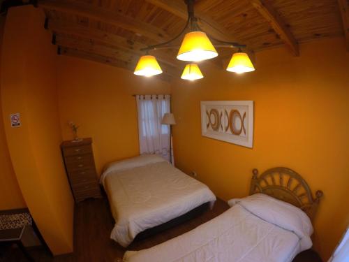 two beds in a room with yellow walls and lights at Attraversiamo in Malargüe