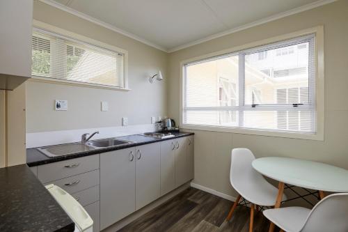 a kitchen with a sink and a table and chairs at Harbour View Motel and Waterfront Apartments in Tauranga