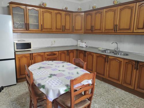 una cocina con armarios de madera, mesa y fregadero en Casa RISAN, en Cañete la Real