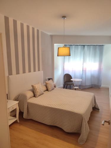 ein Schlafzimmer mit einem Bett, einem Stuhl und einem Tisch in der Unterkunft VUT La Villa in Vilagarcia de Arousa