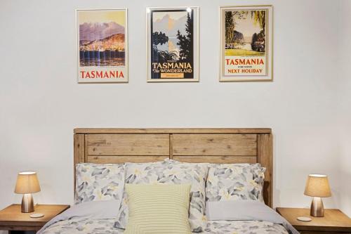 une chambre avec des affiches sur le mur au-dessus d'un lit dans l'établissement Centre Stage - Stroll to the Waterfront, à Hobart
