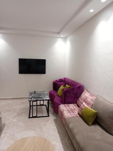 un soggiorno con divano viola e tavolo di شقة مفروشة a Zemmour Touirza