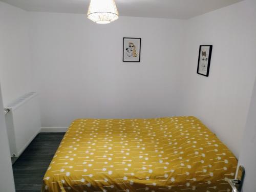 a bed in a room with a yellow blanket at Petite Maison Cosy en Baie in Hillion