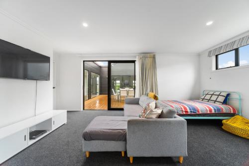 - un salon avec un lit, un canapé et une télévision dans l'établissement Mellow Yellow, à Taupo