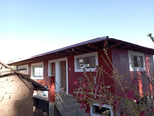 ein rotes Haus mit einer Steinmauer in der Unterkunft Rufino y Lucrecia MUNAY TIKA WASI Posada Oha in Puno