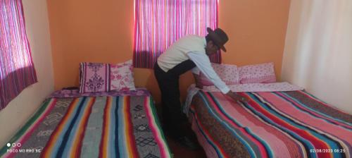 una persona está haciendo dos camas en una habitación en Rufino y Lucrecia MUNAY TIKA WASI Posada Oha en Puno
