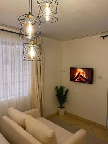 uma sala de estar com um sofá e uma televisão na parede em The Manna Place - South B em Nairobi