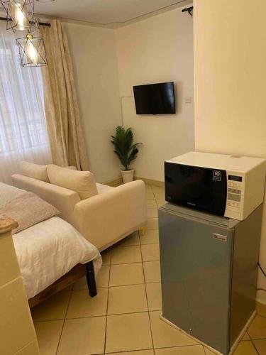 uma sala de estar com uma televisão e um sofá em The Manna Place - South B em Nairobi