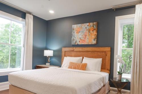 a bedroom with a bed with blue walls and windows at Summit Street Inns in Winston-Salem