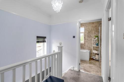 a white hallway with a staircase and a bathroom at Lparking Sleep7 4br 2 Ba in Horsford