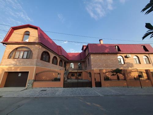 un gran edificio de ladrillo con techo rojo en Gogi's Paradise Guesthouse, en Akhmety