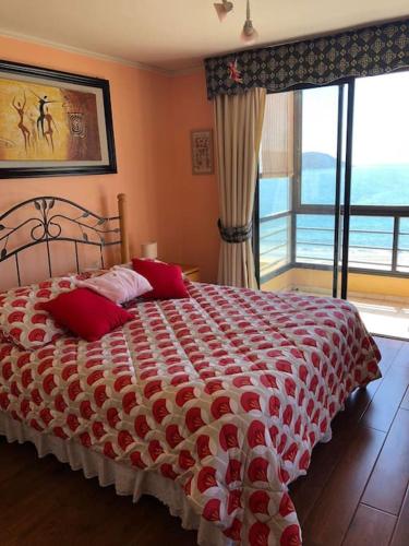 een slaapkamer met een bed met rode kussens en een raam bij Gran departamento frente a la bahía de La Herradura in Coquimbo