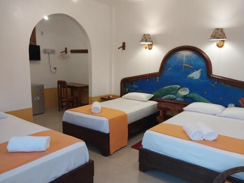 a hotel room with three beds and a painting on the wall at La Casa de Joel in Puerto Villamil