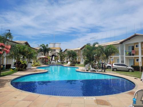 una piscina en un complejo con palmeras y edificios en Duplex com 2 suítes no condomínio Mont Carmelo Aconchego e luxo que você merece, en Porto Seguro