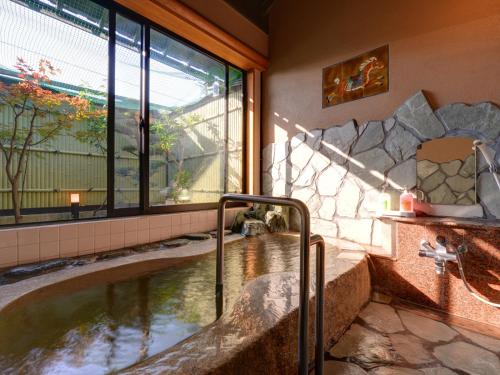 una vasca idromassaggio in una camera con una grande finestra di 北方温泉四季の里　七彩の湯 a Takeo