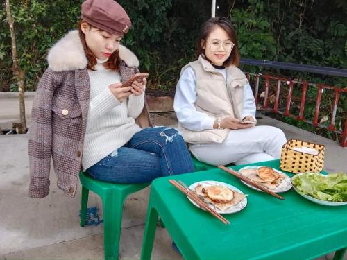 two girls sitting on a bench looking at their cell phone at homestay phô núi suôi giang in Yên Bái