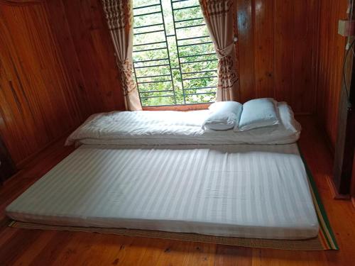 two beds in a room with a window at homestay phô núi suôi giang in Yên Bái