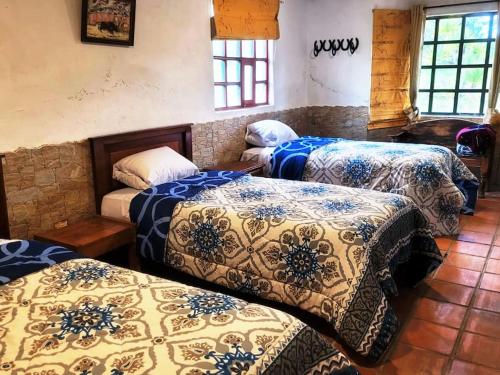 Habitación con 3 camas y mantas azules y blancas. en Hacienda San Mateo, en Cotacachi