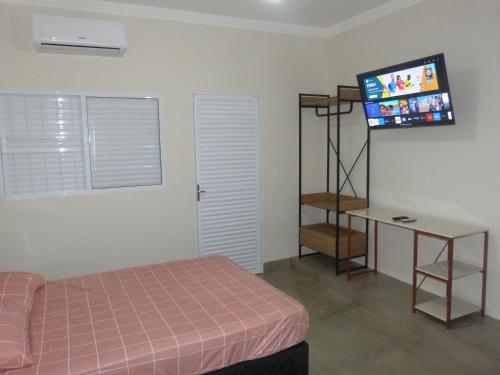 um quarto com uma cama e uma televisão de ecrã plano em Apto Mobiliado Ar Cond Residencial Rios em Barretos