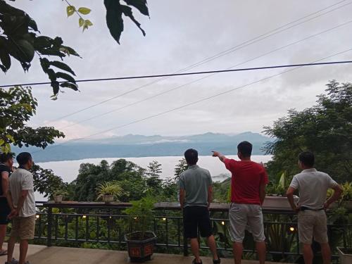 um grupo de homens de pé em uma varanda olhando para a vista em homestay phô núi suôi giang em Yên Bái