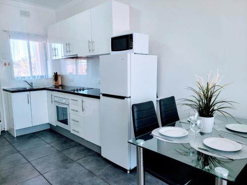 uma cozinha com uma mesa e um frigorífico branco em Zig Zag at Henley ~ BEACH ~ DINING ~ WiFi ~Airport em Henley Beach South