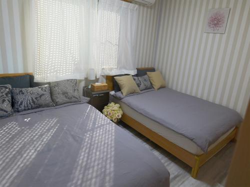 1 dormitorio con 2 camas y ventana en 太平洋を見渡せる海浜リゾート貸切観海荘チャオ, en Momiyama