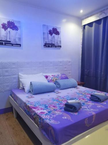 a bedroom with a large bed with a purple comforter at Dew Forest - Romblon Airport Hotel in Alcantara