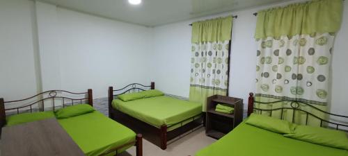 a room with two beds and a table with green sheets at Villa Clara Casa Campestre, Piscina, Naturaleza, Paseo de Río in Melgar