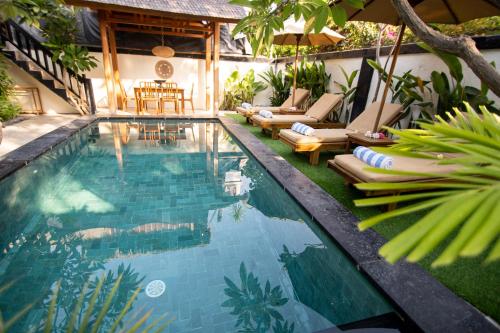 een zwembad met ligstoelen en stoelen naast een huis bij Rumah Singa - Holistic Healing Retreat in Gili Air