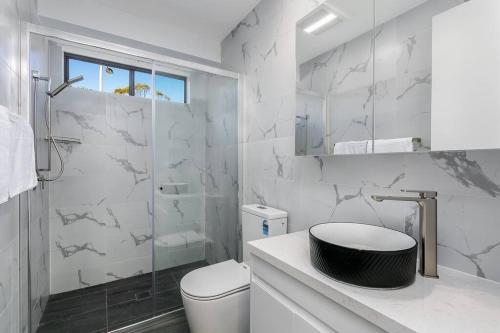 a white bathroom with a toilet and a shower at DY008 - 3 bedroom townhouse - Dee Why in Sydney