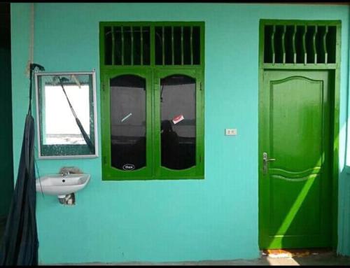 baño con puertas verdes, lavabo y espejo en Jimmy Losmen Nias, en Lagudri