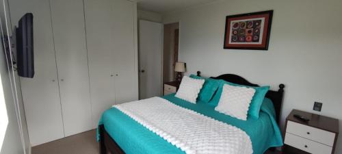 a bedroom with a bed with blue and white pillows at Acogedor Apartamento Constitucion in Constitución