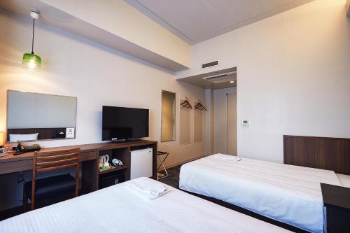 Pokój hotelowy z 2 łóżkami, biurkiem i telewizorem w obiekcie RJ Hotel Naha w mieście Naha
