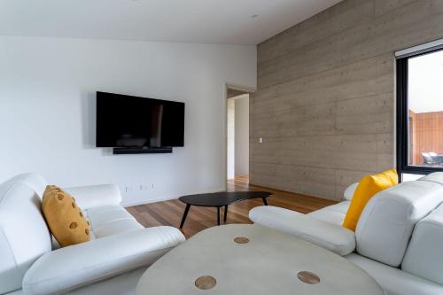 a living room with white furniture and a flat screen tv at The Duke I Private Properties in Gnarabup