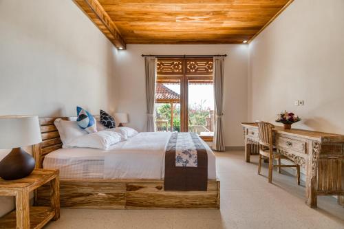 Schlafzimmer mit einem Bett, einem Schreibtisch und einem Fenster in der Unterkunft Atta Villa in Karangasem