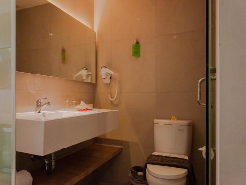 a bathroom with a sink and a toilet and a mirror at Zuri Express Jimbaran in Jimbaran