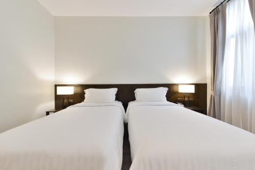 two twin beds in a room with a window at Oldthaiheng Hotel in Bangkok
