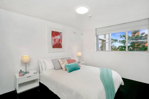a white bedroom with a bed and a window at HARIS - Modern 2BR Apartment with Views in Sydney