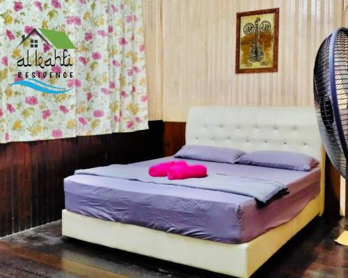 a bed with a pink object on top of it at Qalya 3 Homestay @ Kota Bharu in Kota Bharu